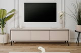 Modernes TV-Lowboard in heller Holzoptik mit schwarzen Akzenten, frontal betrachtet, dekoriert mit Pflanzen und Kerzen.