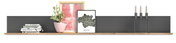 Wandboard mit Dekorationen, darunter Bücher, ein Kaktus in einem rosa Topf, gerahmte Bilder und ein Kerzenhalter mit drei Kerzen, aus frontaler Perspektive.