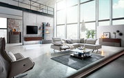 Moderne Eckgarnitur in einem hellen, loftartigen Wohnzimmer mit großen Fenstern und stilvoller Dekoration, seitliche Perspektive.