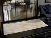 Designer Teppich in einem modernen Wohnzimmer, von oben betrachtet, mit einem eleganten Sessel und großen Fenstern im Hintergrund.