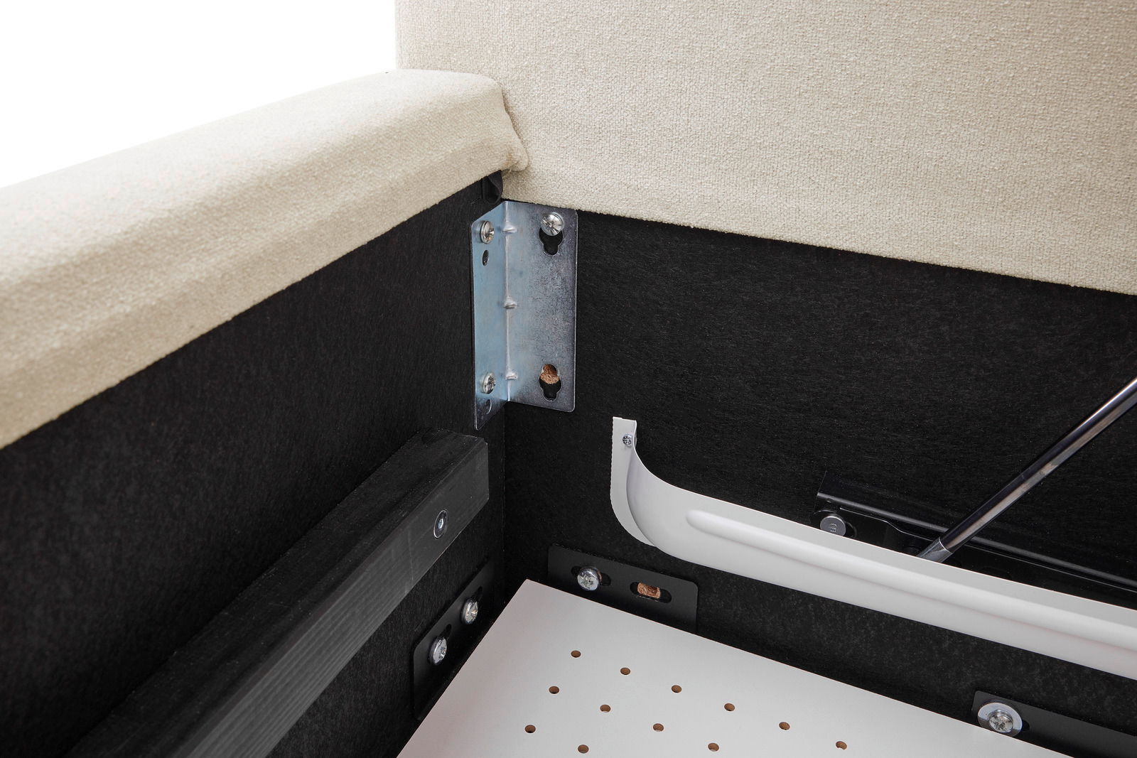 Nahaufnahme der inneren Ecke eines Polsterbettgestells mit Metallbeschlägen und gepolstertem Rahmen.