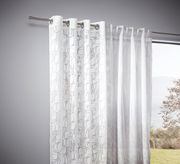 Weiße Vorhänge mit feinem Ornamentmuster, aufgehängt an einer Gardinenstange, seitliche Perspektive mit Blick nach draußen.