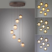 Moderne LED-Pendelleuchte mit mehreren kugelförmigen Glaskörpern, die von einer runden Deckenhalterung in verschiedenen Höhen hängen. Perspektive von unten, um die elegante Anordnung und das warme Licht zu betonen.