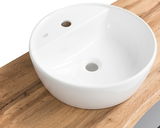 Runder, weißer Waschtisch auf einer Holzplatte, aus der Vogelperspektive fotografiert.