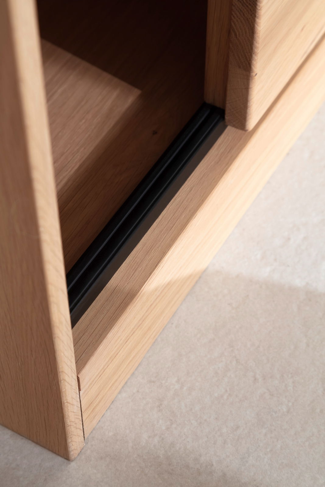 Nahaufnahme einer Holzkante mit schwarzem Akzent, perspektivisch von oben fotografiert.