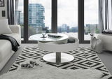 Moderner Couchtisch SUVA mit rundem, drehbarem Design in einem stilvollen Wohnzimmer mit Blick auf die Stadt durch große Fenster.