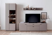Modernes Wohnzimmer-Entertainment-Set in Taupe mit hoher Vitrine mit beleuchtetem Glasfach, TV-Lowboard und Wandregal, frontal aus Augenhöhe fotografiert.