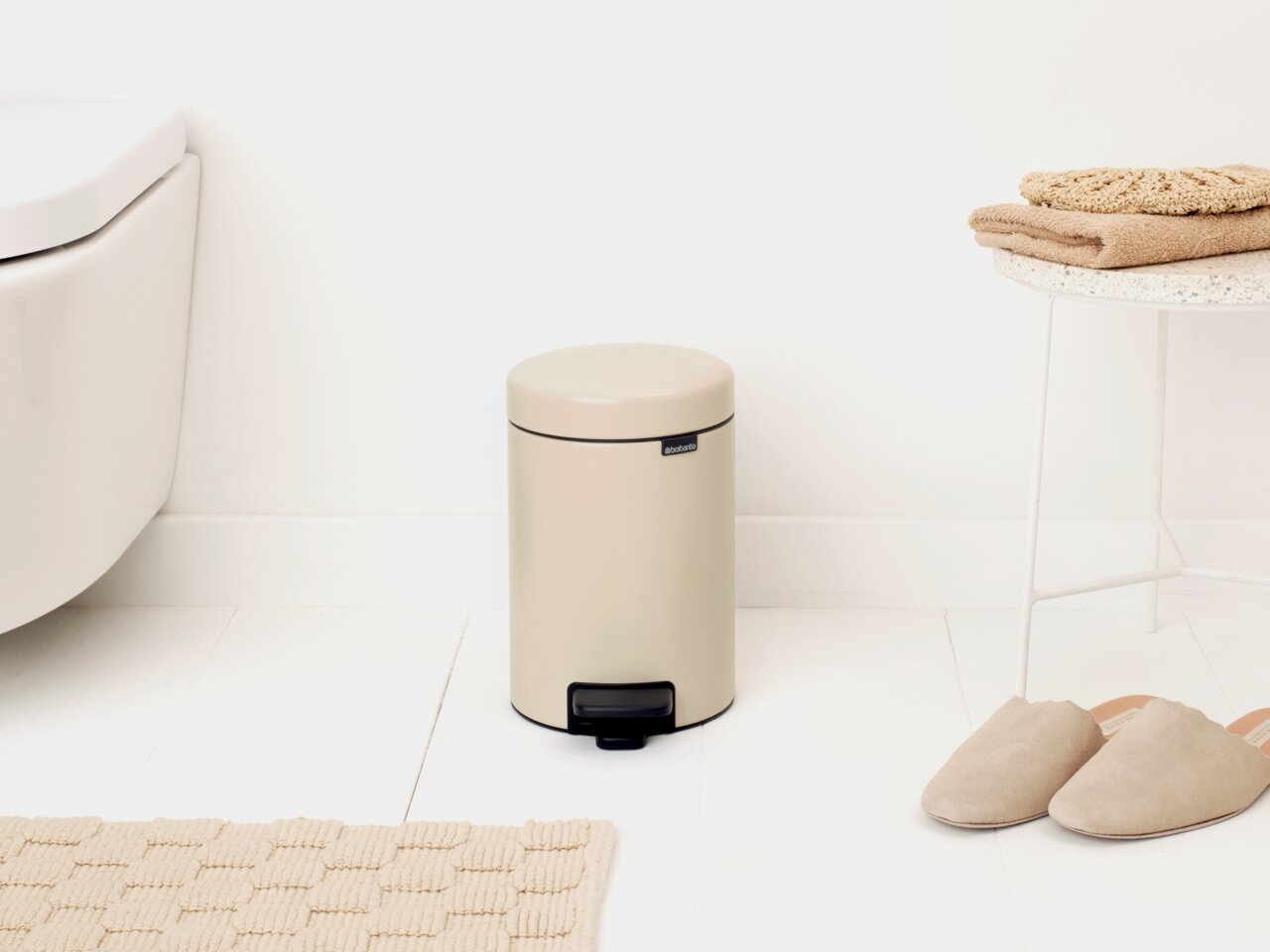 Brabantia Treteimer 3L MINDSET Beiger Treteimer 3L in einem Badezimmer, seitliche Perspektive, neben einem Tisch mit Handtüchern und Hausschuhen.