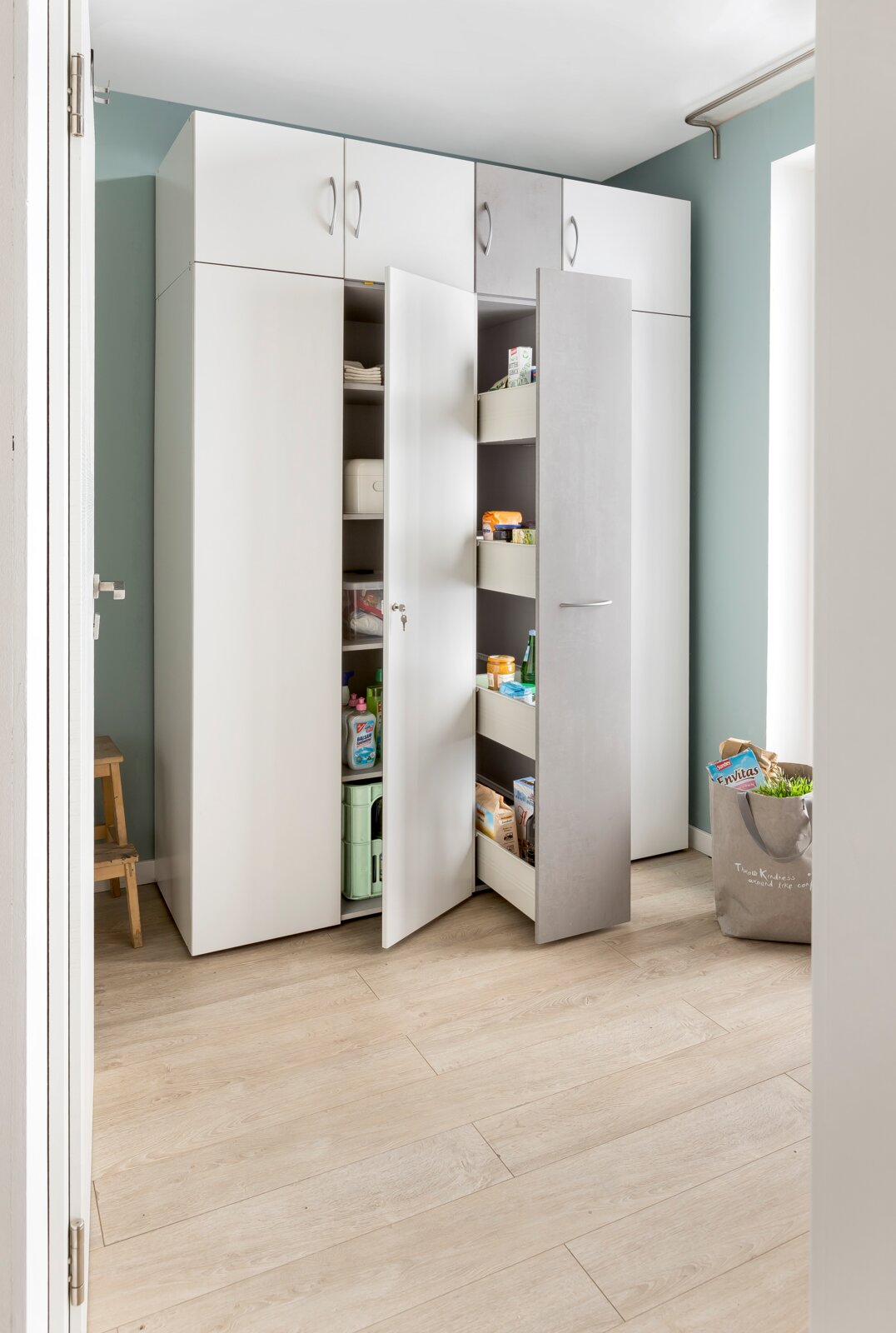 Apothekerschrank in einer modernen Küche, frontal fotografiert, mit geöffneten Türen und sichtbarem Stauraum für Vorräte.