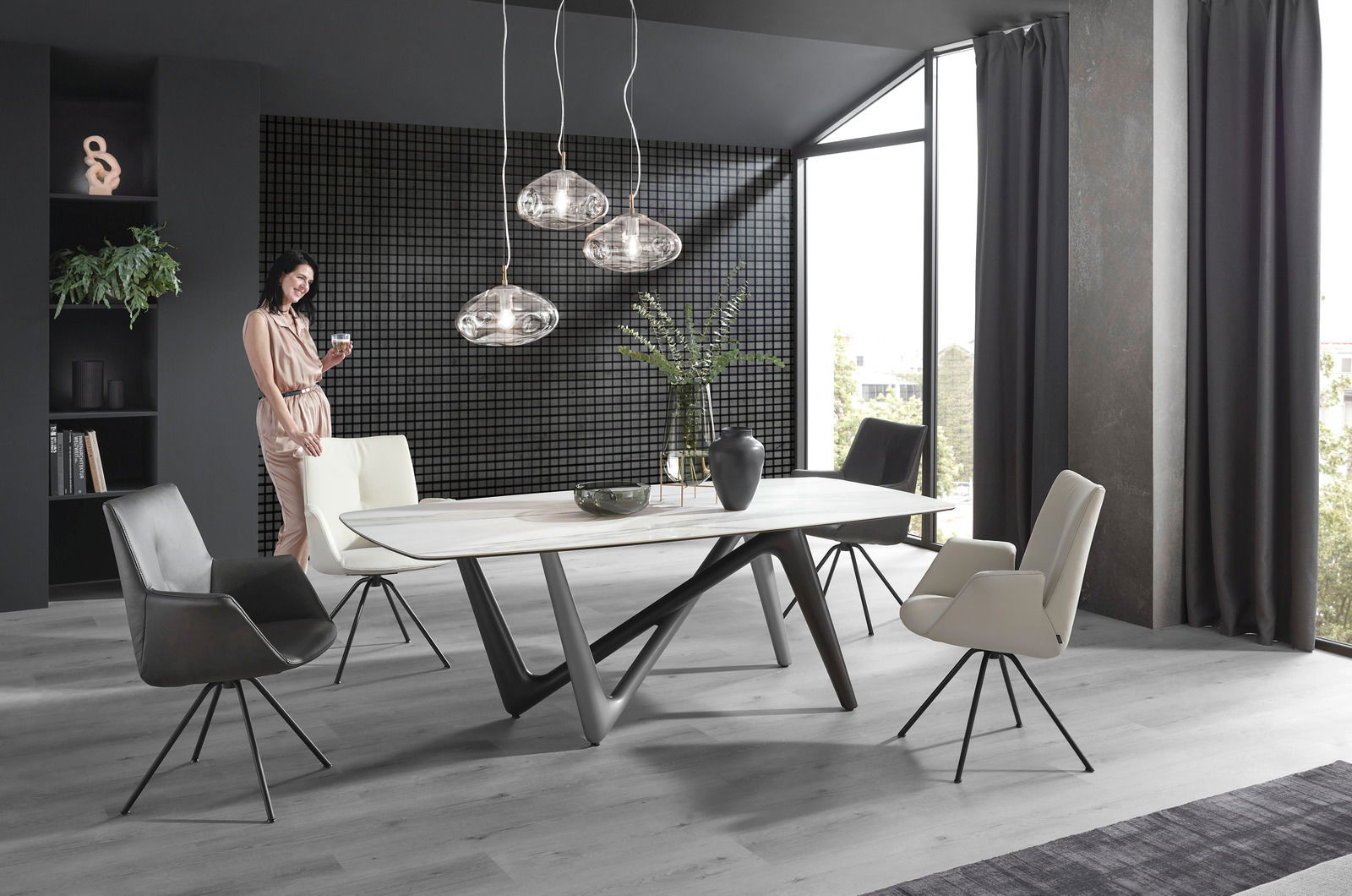 Moderner Essbereich mit stilvollem Tisch und eleganten Sesseln in einem hellen Raum mit großen Fenstern, seitliche Perspektive.
