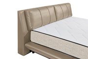 Nahaufnahme eines Polsterbetts mit beigem Kopfteil und weißer Matratze, seitliche Perspektive