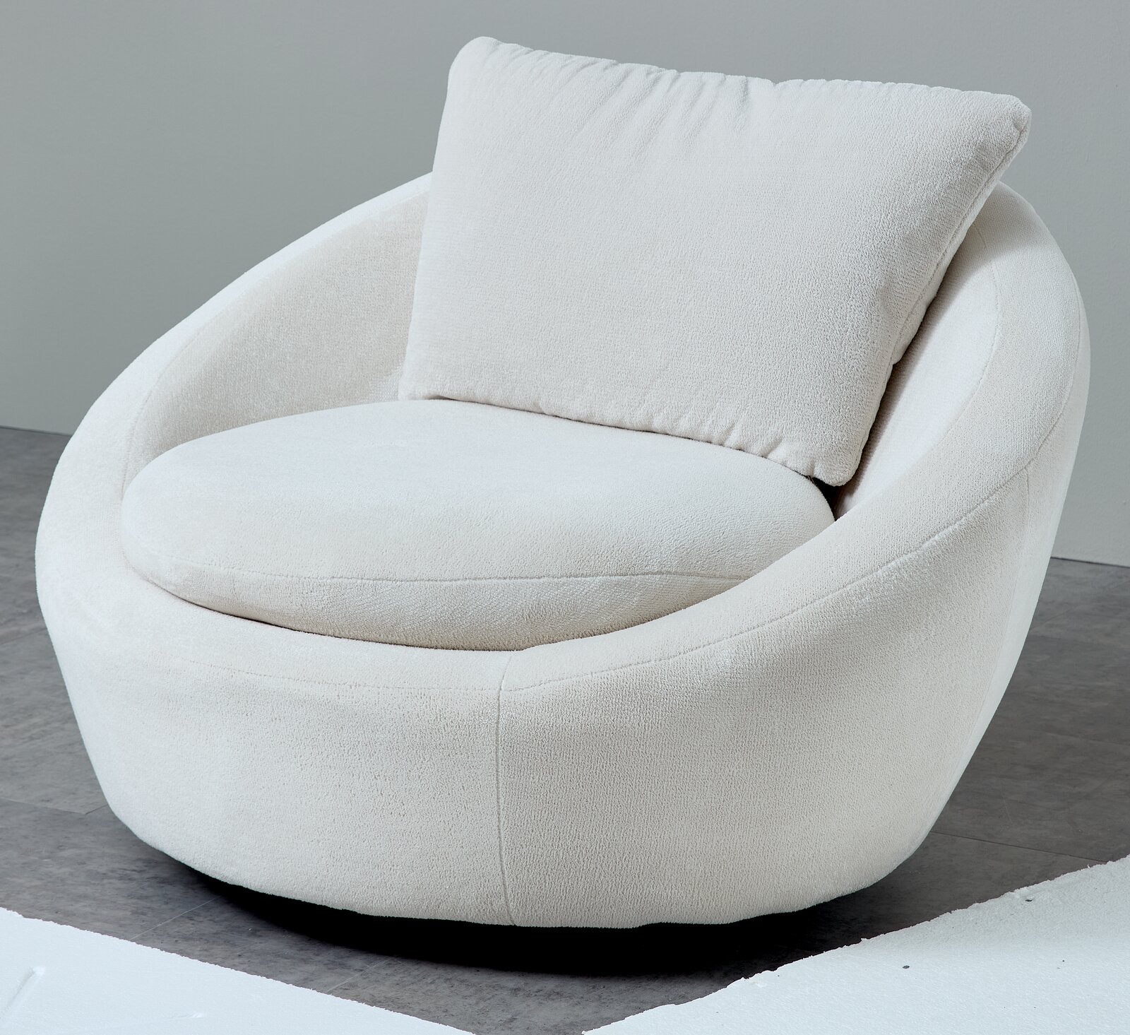 Crèmekleurige, ronde fauteuil met zachte bouclébekleding, een brede zitting en een groot rugkussen, in schuin vooraanzicht tegen een grijze achtergrond.