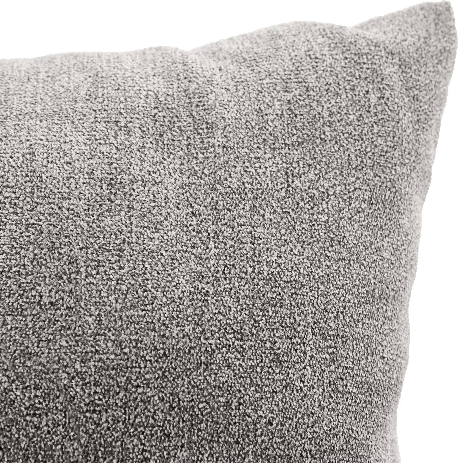 Nahaufnahme eines grauen Sofakissens mit weicher Textur, perspektivisch von der Seite aufgenommen.