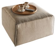 Quadratischer, beige gerippter Hocker mit einem runden Holztablett, darauf zwei Tassen Kaffee und Pralinen, aus einer leicht erhöhten Perspektive.