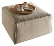 Quadratischer, beige gerippter Hocker mit einem runden Holztablett, darauf zwei Tassen Kaffee und Pralinen, aus einer leicht erhöhten Perspektive.