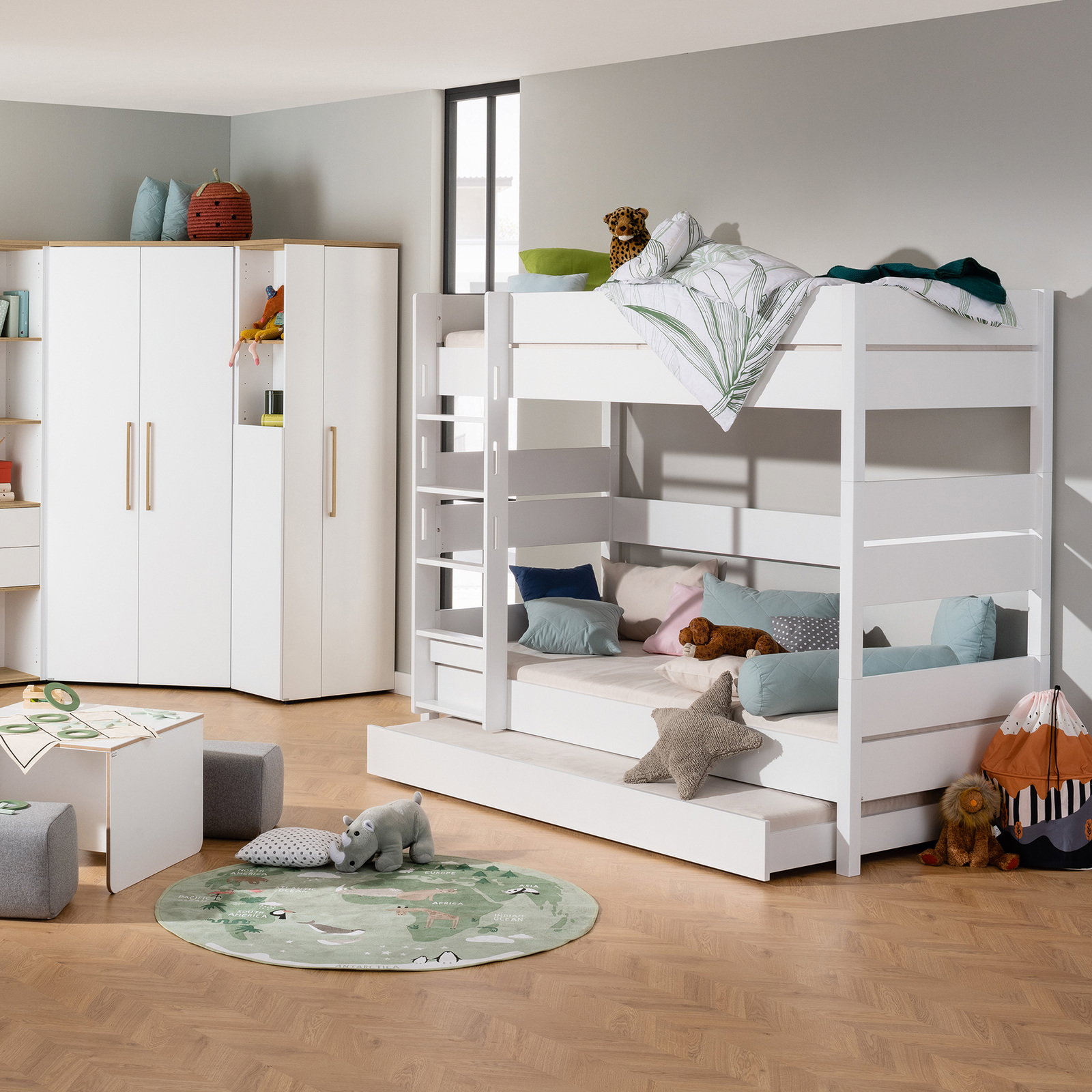 Weißes Etagenbett in einem Kinderzimmer, seitliche Perspektive, mit bunten Kissen und Spielzeug dekoriert.