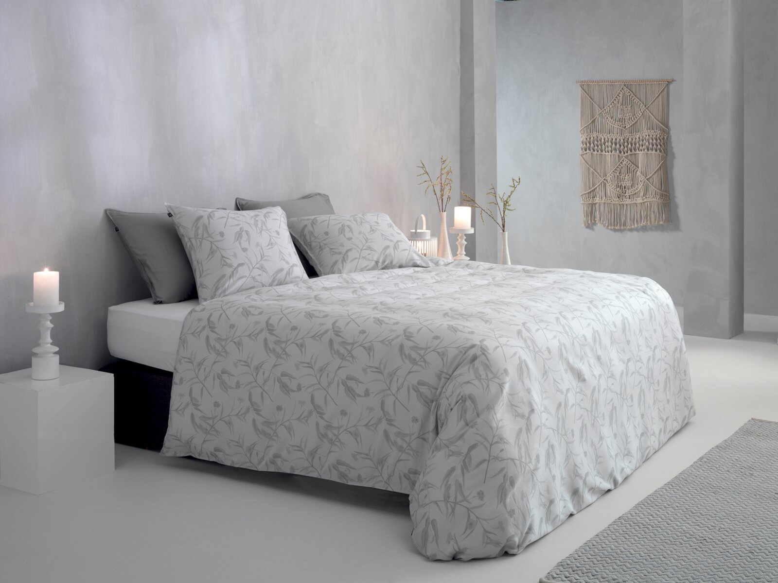Bett mit grauer, floraler Bettwäsche in einem modernen, minimalistisch eingerichteten Raum, seitliche Perspektive