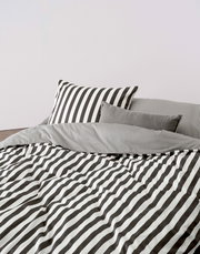 Bettwäsche-Set mit schwarz-weißen Streifen, bestehend aus einem Kissenbezug und einer Decke, aus der Perspektive von vorne fotografiert.