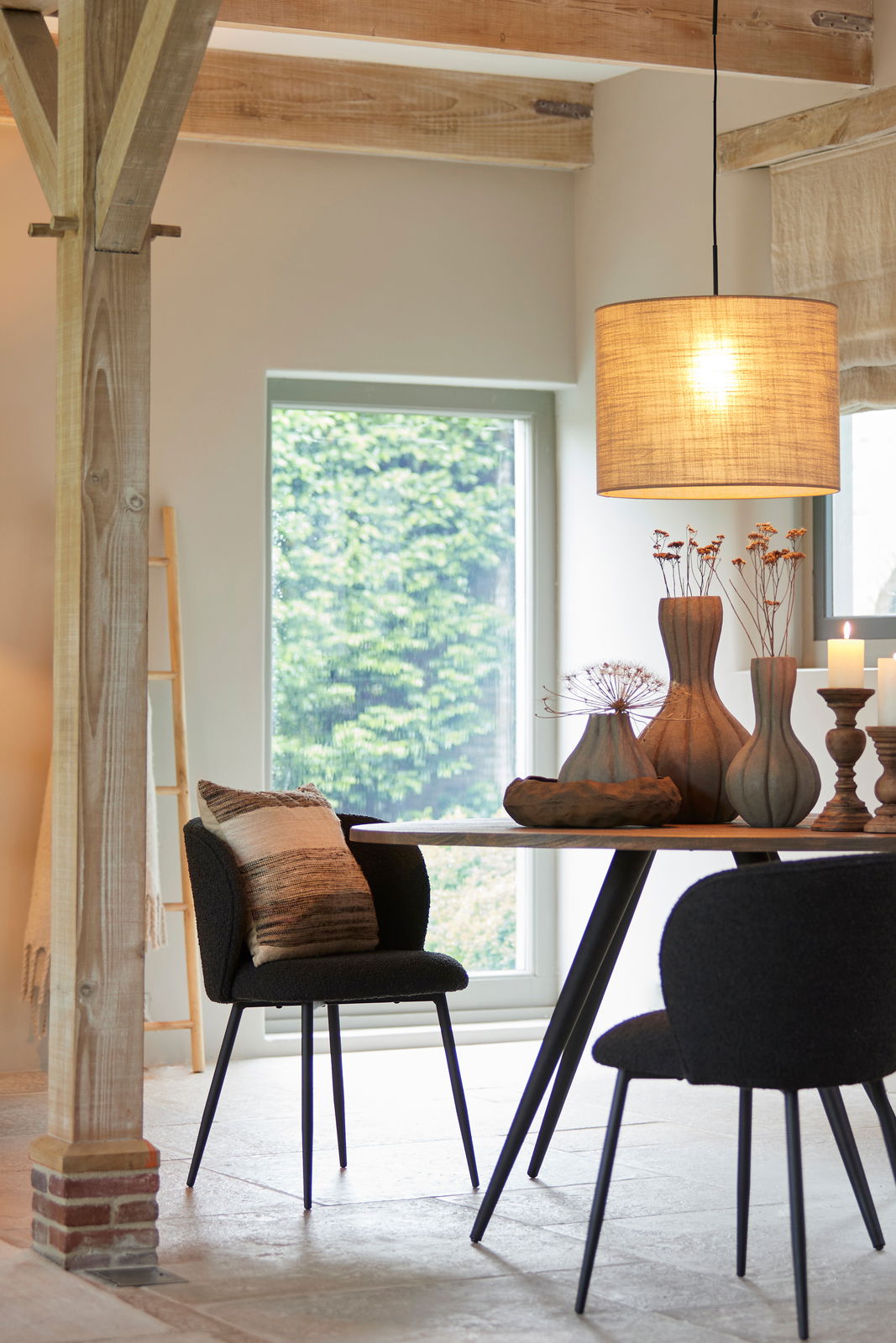 Hängelampe in einem modernen Esszimmer, Perspektive von der Seite, mit einem runden Tisch und dekorativen Vasen darunter.