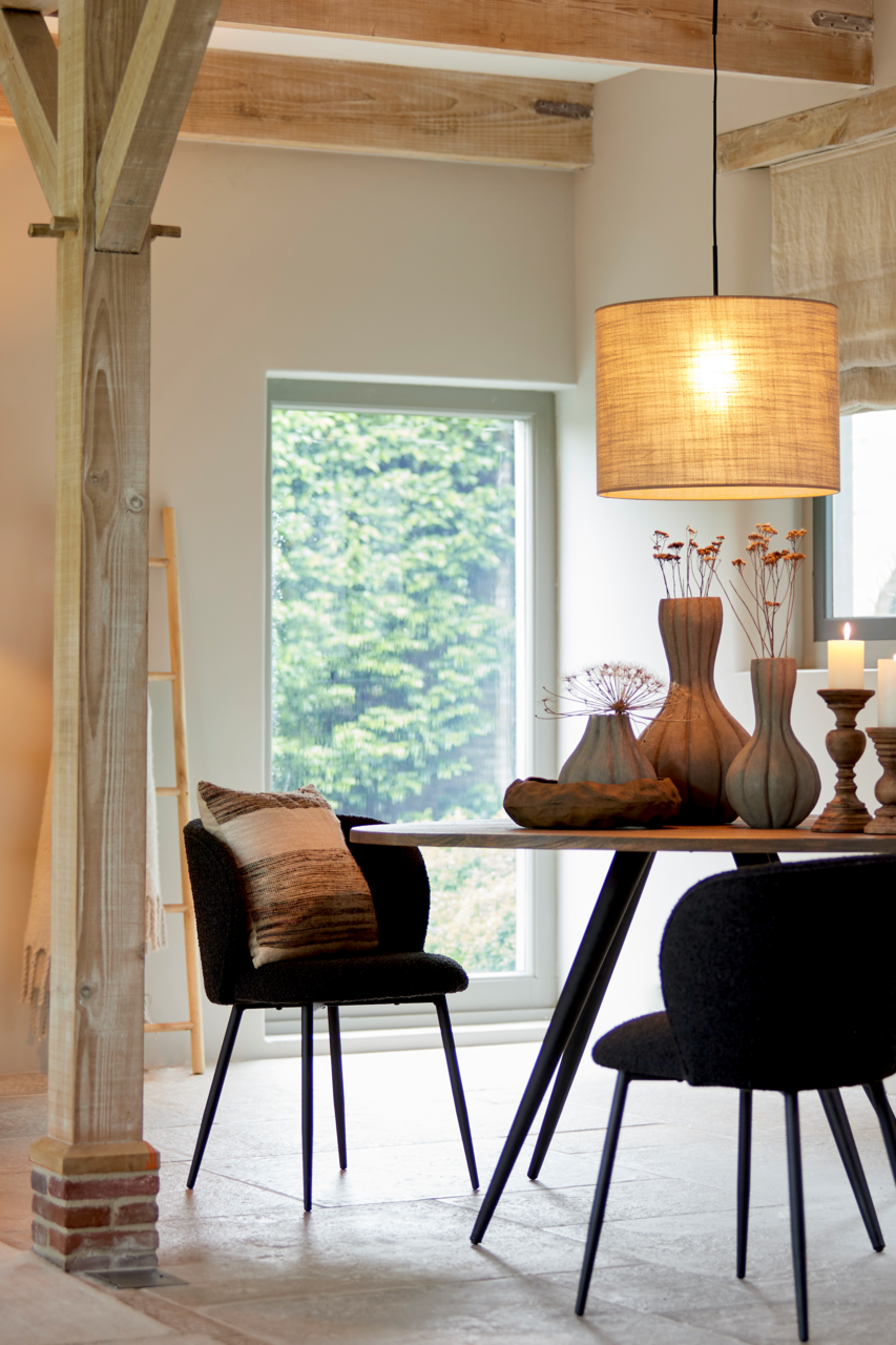 Hängelampe in einem modernen Esszimmer, Perspektive von der Seite, mit einem runden Tisch und dekorativen Vasen darunter.