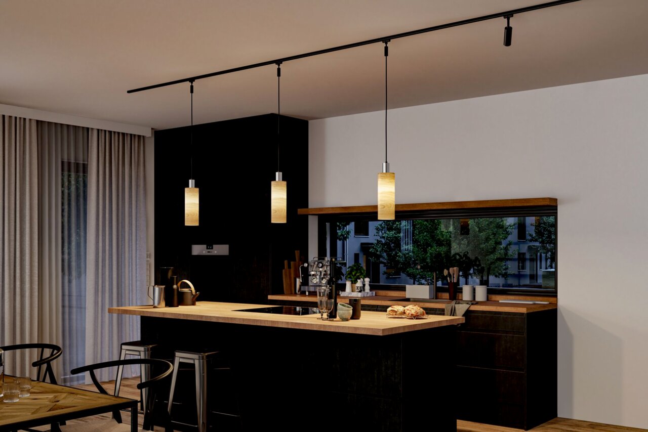 Moderne keuken met drie hangende decoratieve lampen van het merk Vitus boven een kookeiland, zijaanzicht