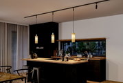 Moderne keuken met drie hangende decoratieve lampen van het merk Vitus boven een kookeiland, zijaanzicht
