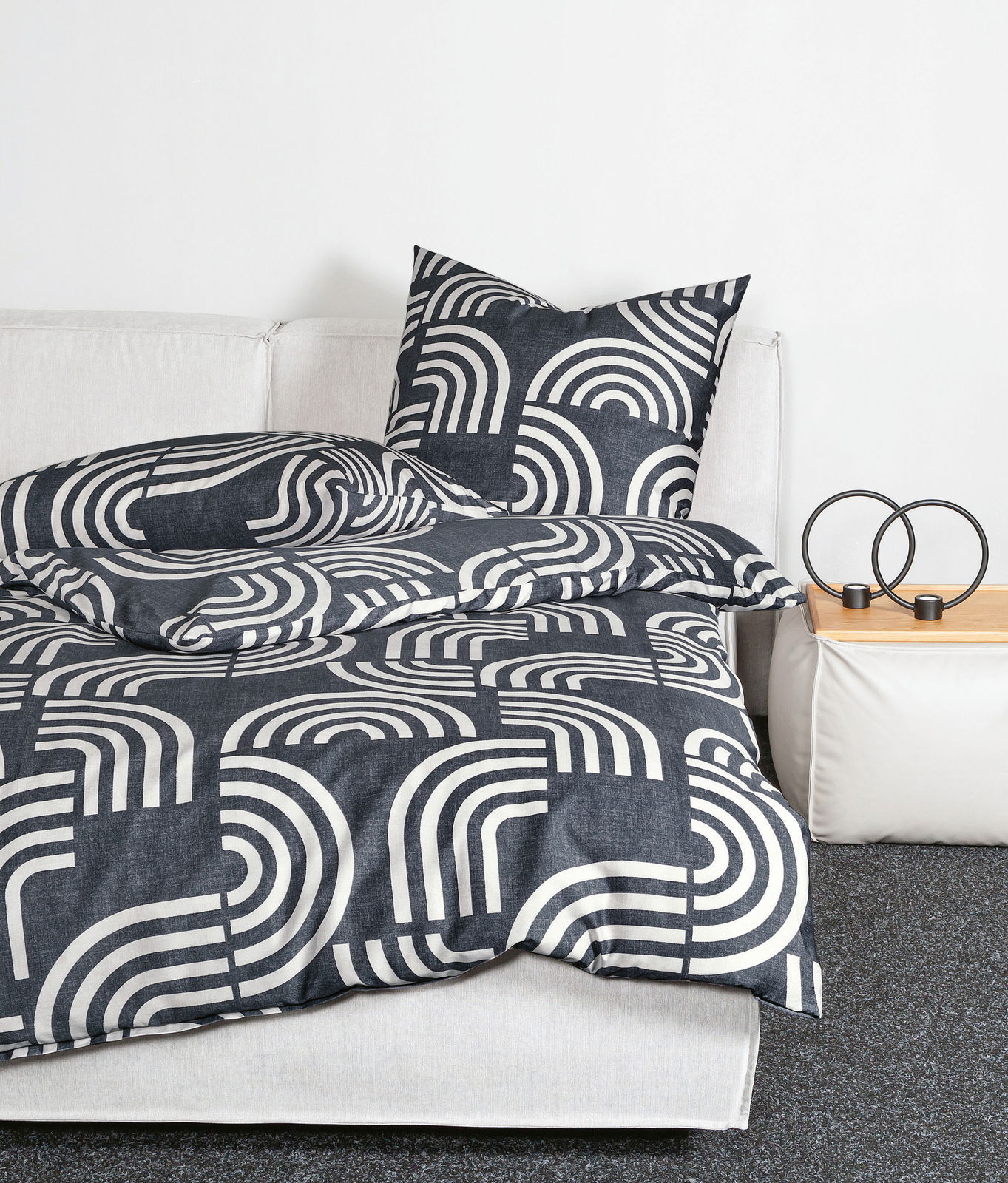 Bettwäsche-Set Janine PALERMO in Schwarz-Weiß mit geometrischem Muster, auf einem weißen Sofa drapiert, seitliche Perspektive