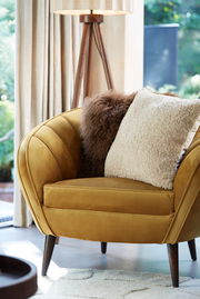 Beiges Kissen LINA 45x45 cm auf einem senfgelben Sessel, seitliche Perspektive