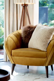 Beiges Kissen LINA 45x45 cm auf einem senfgelben Sessel, seitliche Perspektive