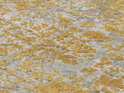 Nahaufnahme eines Designer-Teppichs mit goldenen und grauen Mustern aus schräger Perspektive.