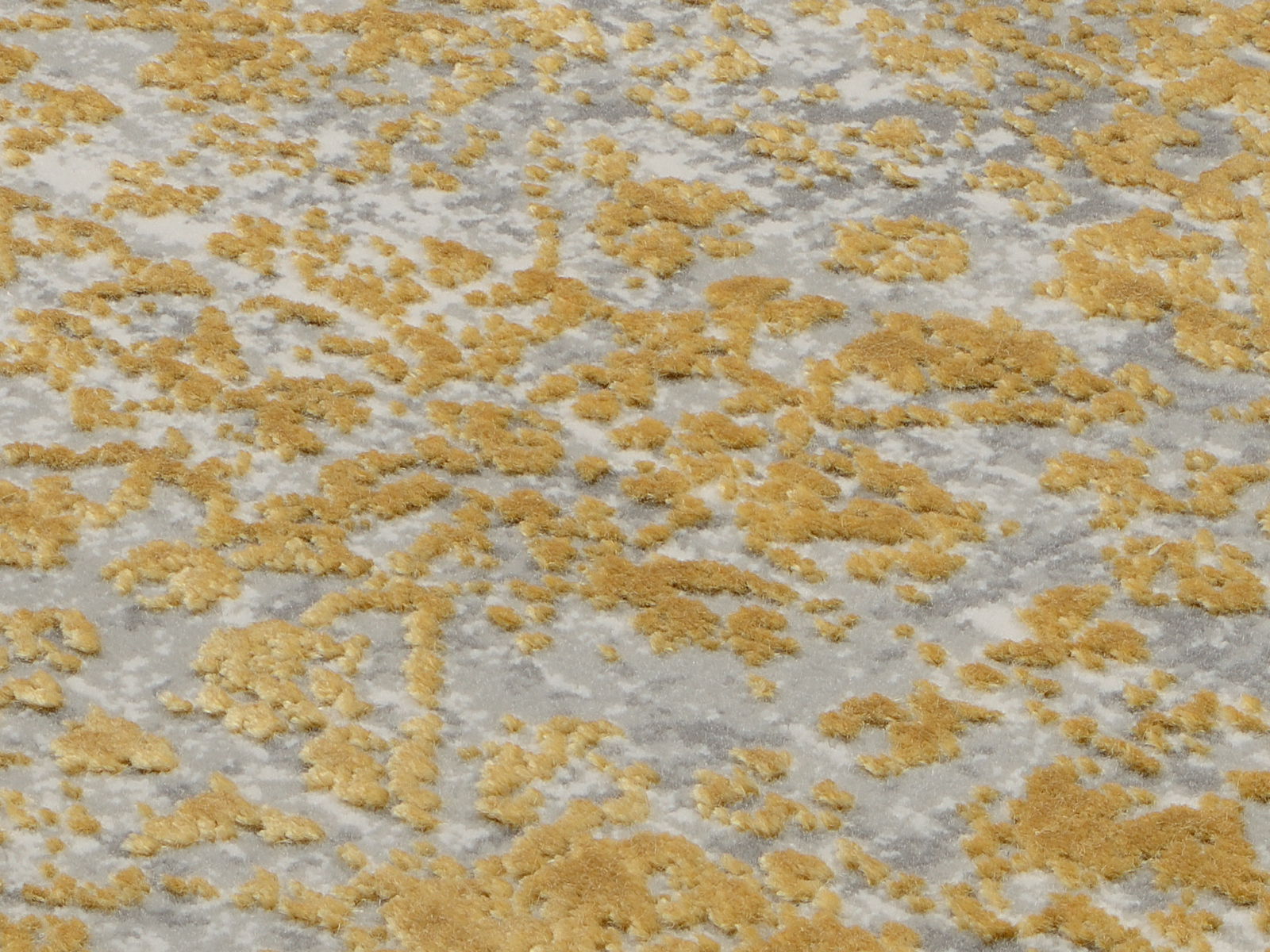 Nahaufnahme eines Designer-Teppichs mit goldenen und grauen Mustern aus schräger Perspektive.