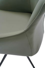 Nahaufnahme eines Armlehnstuhls mit grünem Lederbezug und schwarzen Metallbeinen, seitliche Perspektive