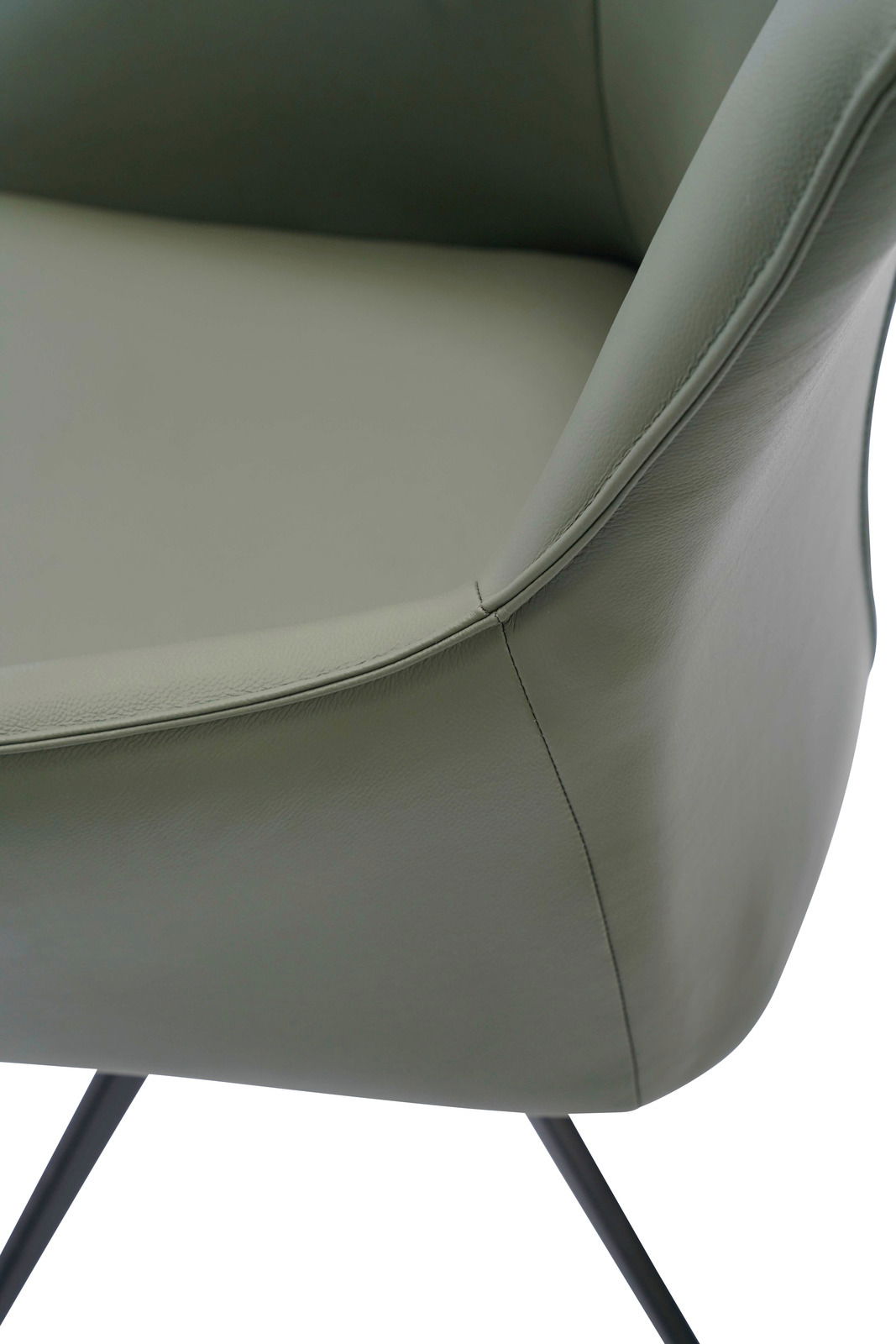 Nahaufnahme eines Armlehnstuhls mit grünem Lederbezug und schwarzen Metallbeinen, seitliche Perspektive