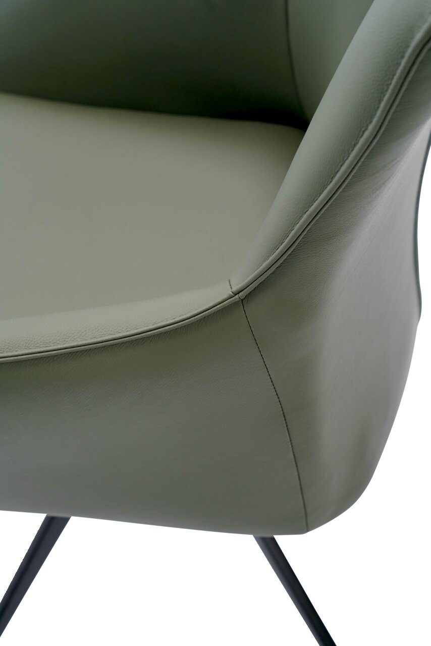 Nahaufnahme eines Armlehnstuhls mit grünem Lederbezug und schwarzen Metallbeinen, seitliche Perspektive