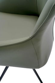 Nahaufnahme eines Armlehnstuhls mit grünem Lederbezug und schwarzen Metallbeinen, seitliche Perspektive