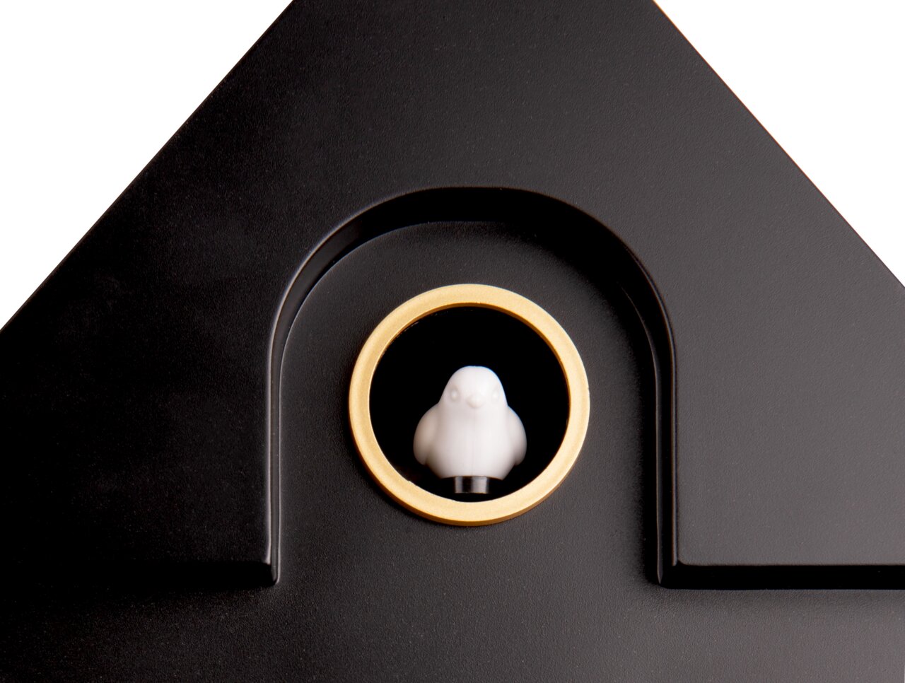 Nahaufnahme einer schwarzen Wanduhr mit einem goldenen Ring und einer kleinen weißen Figur in der Mitte, die wie ein Vogel aussieht. Die Perspektive zeigt die obere Hälfte der Uhr.