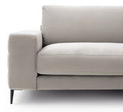 Nahaufnahme eines modernen, beigen Sofas mit Armlehne und schwarzen Beinen, seitliche Perspektive.