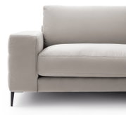 Nahaufnahme eines modernen, beigen Sofas mit Armlehne und schwarzen Beinen, seitliche Perspektive.