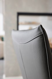 Nahaufnahme der Rückseite eines grauen Armlehnstuhls aus Leder, seitliche Perspektive