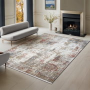 Moderner Wohnzimmerteppich im Vintage-Look in Creme, Grau, Blau und Rot vor Kamin und Sofa, schräg von oben aus der Raumansicht fotografiert