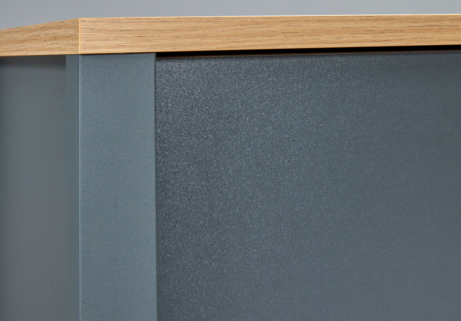 Nahaufnahme eines Schrankaufsatzes mit grauer Oberfläche und Holzleiste, seitliche Perspektive.