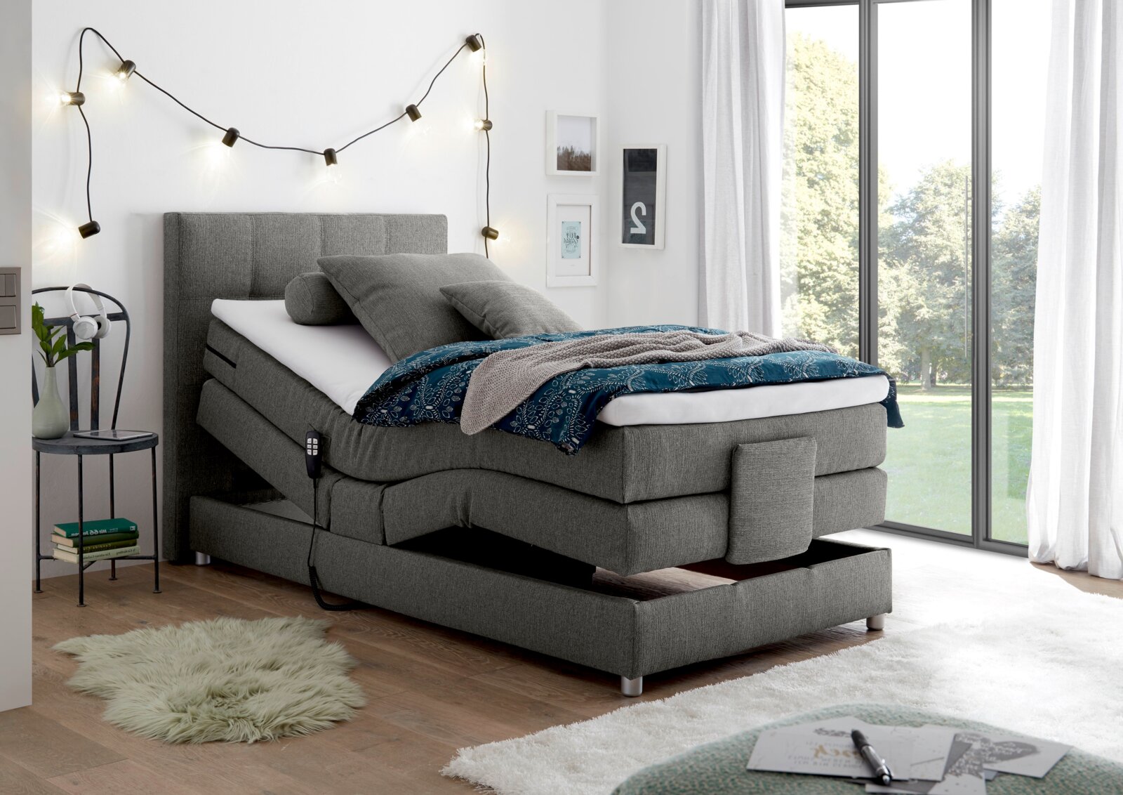 Graues Boxspringbett mit verstellbarem Kopfteil in modernem Schlafzimmer, seitliche Perspektive