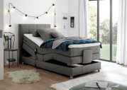 Graues Boxspringbett mit verstellbarem Kopfteil in modernem Schlafzimmer, seitliche Perspektive