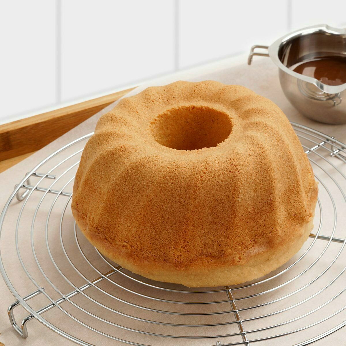 Runder Tortenrost aus verchromtem Metall mit einem Gugelhupf darauf, seitliche Perspektive