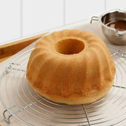 Runder Tortenrost aus verchromtem Metall mit einem Gugelhupf darauf, seitliche Perspektive