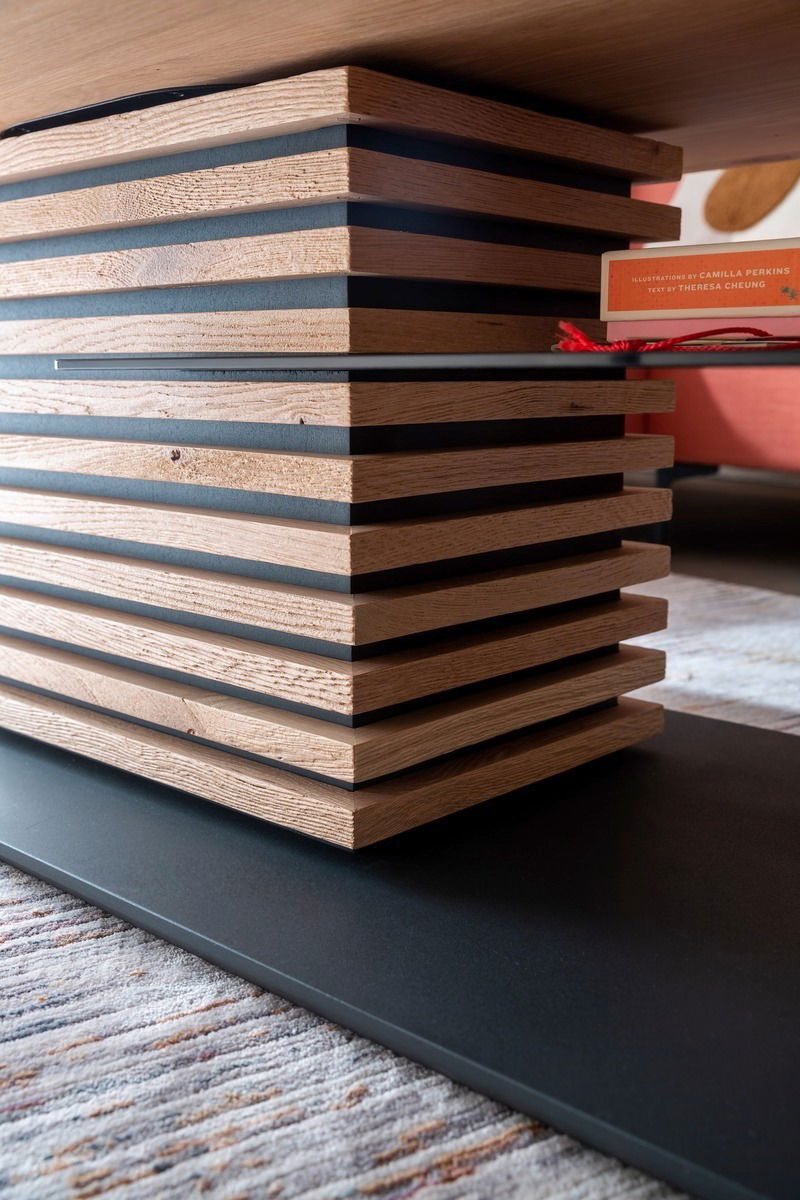 Nahaufnahme eines modernen Couchtischs mit gestapelten Holz- und Metallelementen, seitliche Perspektive.