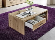 Moderner Couchtisch aus Holz mit Schublade, auf lila Teppich, aus seitlicher Perspektive fotografiert.