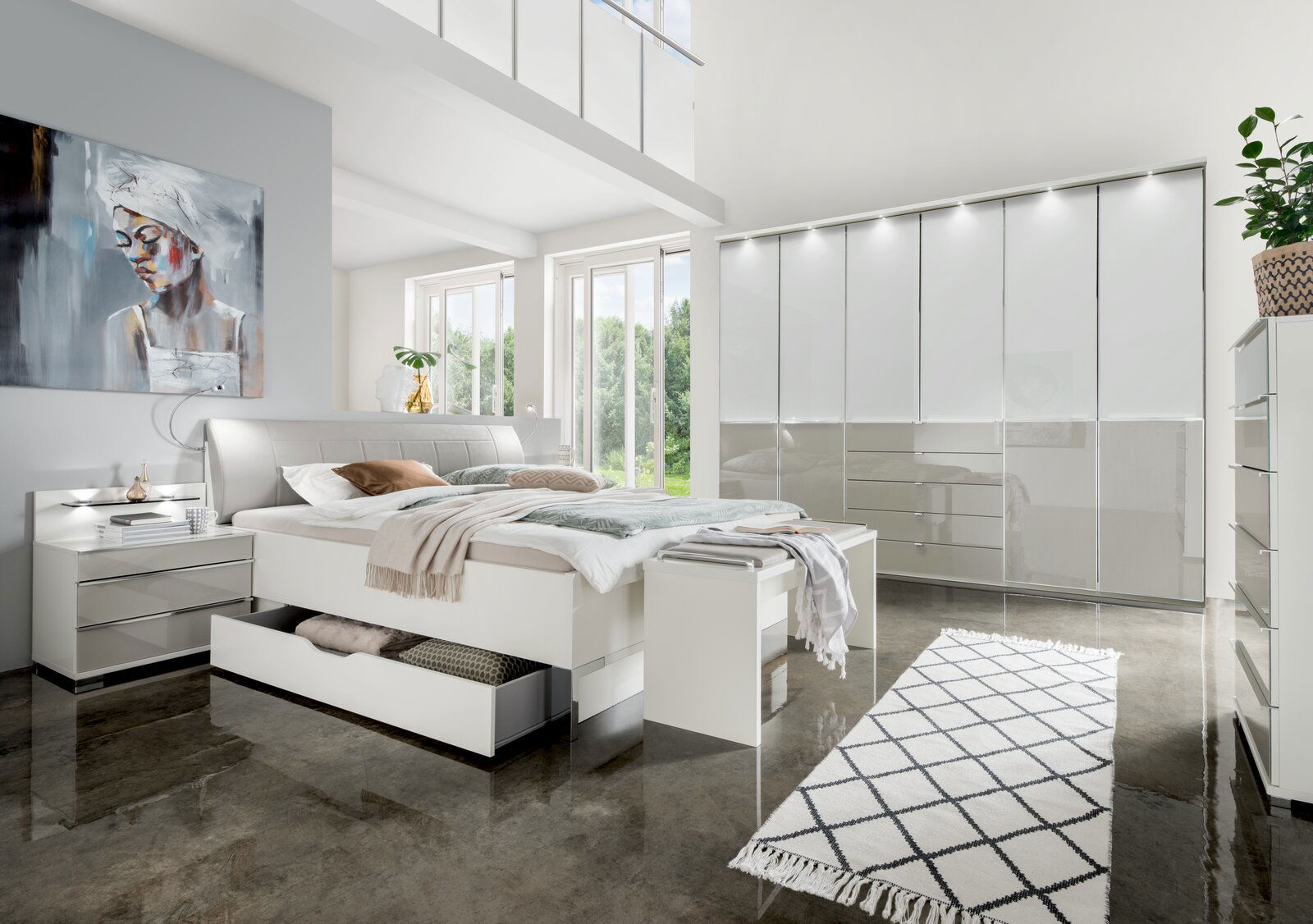 Modernes Futonbett in einem hellen Schlafzimmer mit großen Fenstern, stilvollen Möbeln und einem Kunstwerk an der Wand, aus der Perspektive von vorne links.