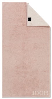 Duschtuch in zartem Rosa mit umgeschlagener Ecke, zeigt das Etikett und die Marke JOOP! in der unteren rechten Ecke. Draufsicht.