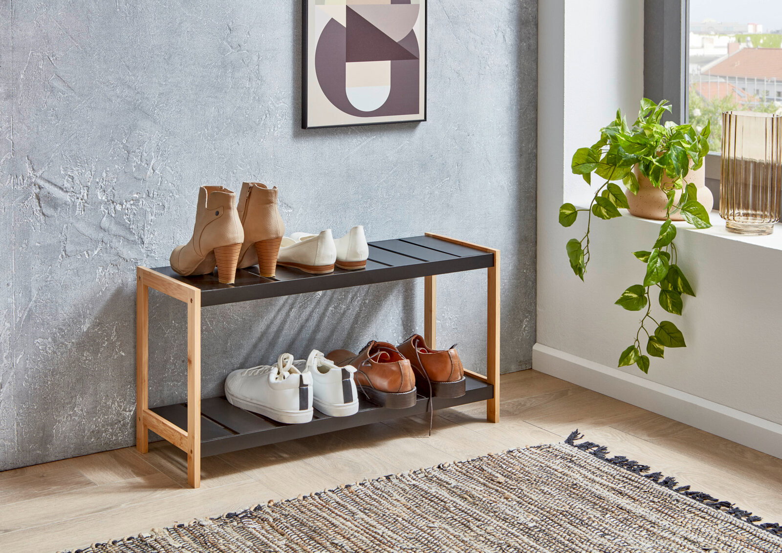 MID.YOU Schuhregal SMALL Zweistöckiges Schuhregal aus hellem Holz und schwarzen Ablagen im Flur, mit mehreren Paar Schuhen darauf, seitliche Frontansicht in leichtem Winkel.